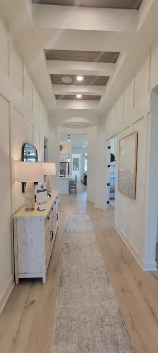 A welcoming hallway with stylish paneling, wood flooring, and warm lighting.