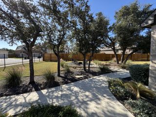 Street view A serene landscaped garden with mature trees and pathways in Parkside on the River by Coventry Homes (Georgetown, TX).