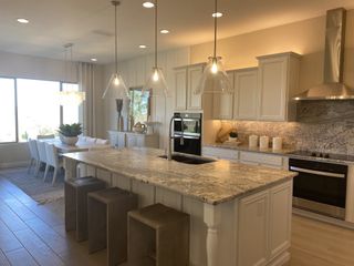 A bright kitchen with a granite island, white cabinets, and stainless steel appliances flows into a dining area, creating an inviting space.