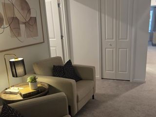 A well-lit upstairs loft with plush carpet, neutral décor, and a relaxing seating area for reading or lounging.