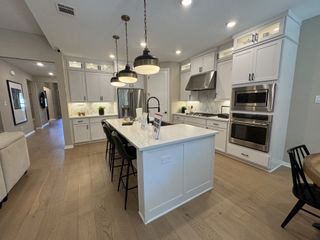 A stunning open-concept kitchen featuring white cabinetry, stainless steel appliances, and a large island with pendant lighting, perfect for entertaining and everyday living.