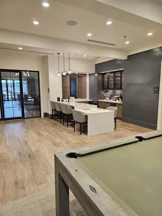 A chic lounge area featuring a pool table, cozy seating, and an open-concept kitchen for casual entertainment.