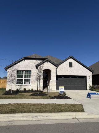 A modern single-story home with a dark garage in Rosenbusch Ranch by D.R. Horton (Leander, TX).