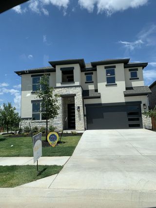 Street view Modern two-story home with stone and stucco exterior in Retreat at San Gabriel by Brightland Homes (Georgetown, TX).