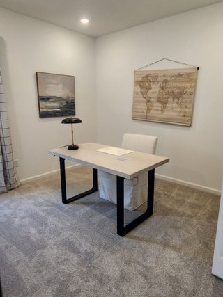 A chic home office with a sleek desk, elegant chair, modern lamp, and coastal artwork creating a serene workspace.