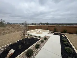 A covered patio with modern outdoor seating and a backyard fire pit in Veramendi by Brightland Homes (New Braunfels, TX).