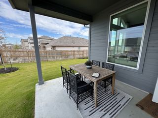 Model Home A cozy patio with a wooden table, modern chairs, and a lush lawn view. Perfect for outdoor dining and relaxation.