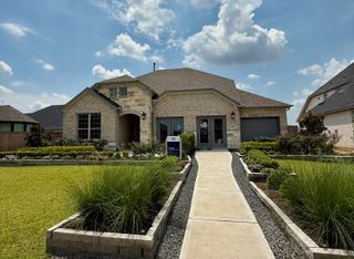 A charming light brick home with a well-manicured yard in Arabella on the Prairie by Pulte Homes (Richmond, TX).