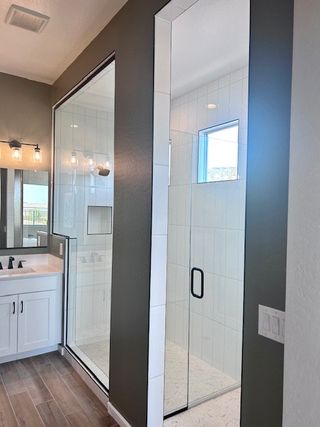 A modern bathroom with a sleek glass shower, white vanity, and elegant lighting fixtures for a stylish touch.