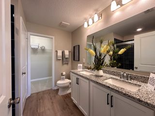 A sleek bathroom with a double vanity, granite countertops, and modern lighting fixtures.
