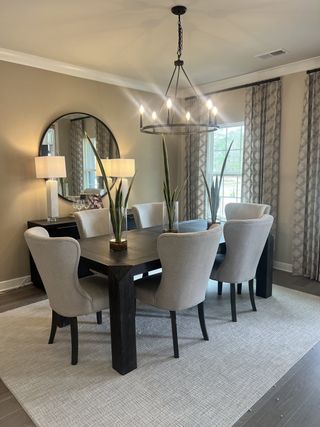 A modern dining room with a dark wood table, plush chairs, stylish chandelier, and elegant decor.