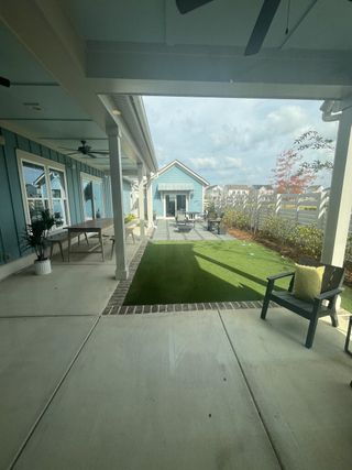 Model Home A cozy backyard patio with covered seating, lush lawn, and garden views, perfect for relaxation and outdoor gatherings.