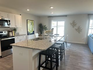 Model Home A bright kitchen with granite countertops, sleek stainless steel appliances, and stylish bar seating.