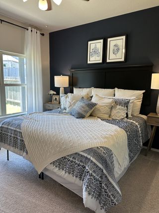 A cozy bedroom featuring a dark accent wall, elegant bed linens, and warm lighting for a relaxing ambiance.