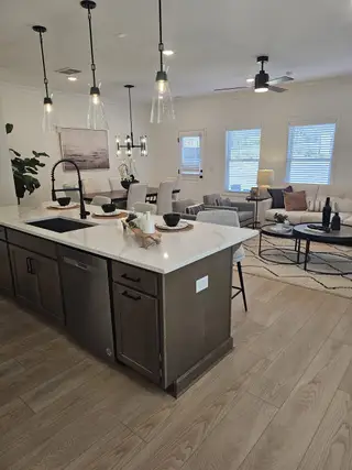 A modern kitchen and living area featuring pendant lighting, a spacious island, and cozy seating arrangements.