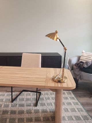 A stylish home office with a sleek wooden desk, brass lamp, cozy chair, and a patterned rug for a modern touch.
