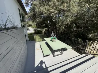 Model Home A serene deck with a green picnic table, surrounded by lush trees, ideal for outdoor relaxation and gatherings.