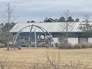 A modern playground with unique climbing structures in Nexton - Midtown by DRB Homes (Summerville, SC), set against a green backdrop.
