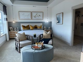 A cozy bedroom with elegant seating, pendant lighting, and artful wall decor, complemented by a spacious walk-in closet.