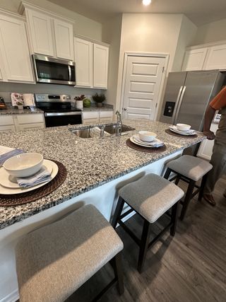 A modern kitchen with granite countertops, a sleek island with seating, and stainless steel appliances.