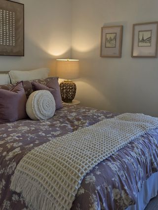 A cozy bedroom with floral bedding, plush pillows, and warm lighting, creating a serene and inviting atmosphere.
