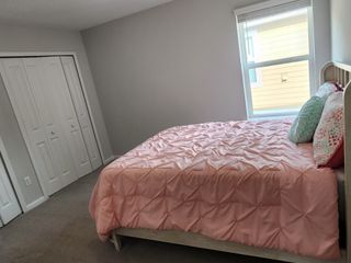 Model Home Cozy bedroom with a pink, tufted comforter, bright window, and dual-door closet for ample storage.