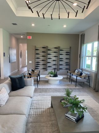 A modern living room featuring a sleek chandelier, plush seating, and stylish decor with contemporary shelving.