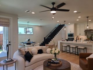 Model Home A modern open-plan living space featuring a sleek kitchen, cozy seating area, and stylish dining nook with contemporary lighting.