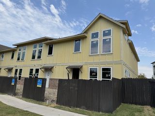 A modern yellow townhome with large windows and brick accents in Koenig Townhomes by Milestone Community Builders (Austin, TX).