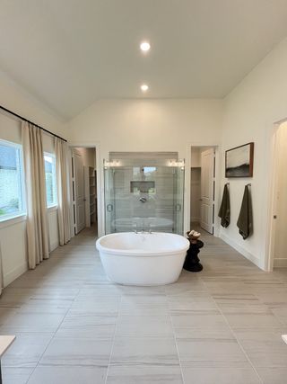 Model Home A luxurious bathroom featuring a freestanding tub, glass-enclosed shower, and large windows for natural light.