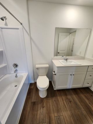 Model Home A modern bathroom with a sleek white vanity, wood-style flooring, and a classic bathtub.