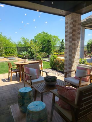 Model Home A cozy patio with chic seating, vibrant cushions, and a lush garden view for perfect outdoor relaxation.