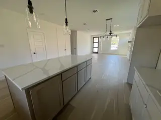 A modern kitchen with sleek countertops, pendant lighting, and light wood flooring, perfect for a stylish home.