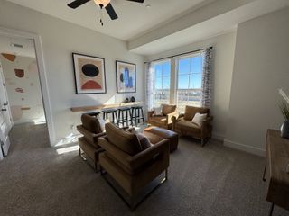 Model Home A cozy living area with soft lighting, stylish artwork, comfortable seating, and large windows offering ample natural light.