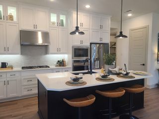 A modern kitchen with a large island, pendant lighting, and sleek appliances, highlighted by stylish cabinetry.