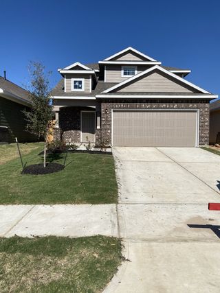 Street view A charming two-story home with a mix of brick and siding, a two-car garage, and a neatly landscaped yard in Robins Landing by CastleRock Communities (Houston, TX).