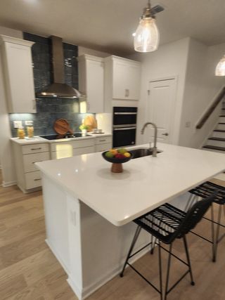 A modern kitchen with sleek white cabinets, a central island, and chic pendant lighting.