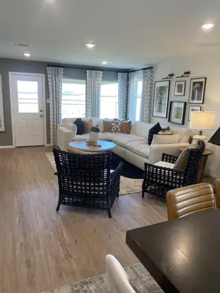 A cozy living room featuring a sectional sofa, stylish armchairs, and elegant wall art, with abundant natural light.