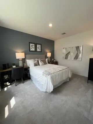 A cozy bedroom featuring a soft carpet, elegant dark accent wall, and stylish decor with modern lighting.