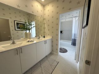 A bright bathroom featuring dual sinks, star-patterned walls, and a stylish geometric rug.
