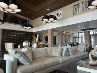 A modern living area featuring a plush sectional, stylish lighting, and artistic touches with brick accents and a wooden ceiling.