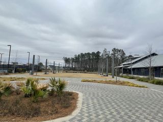 A spacious park with modern amenities in Nexton - Midtown by DRB Homes, Summerville, SC, featuring lush greenery and paved paths.