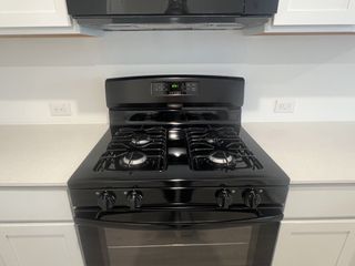 Model Home A sleek black gas stove set against crisp white cabinetry and countertops in a modern kitchen.