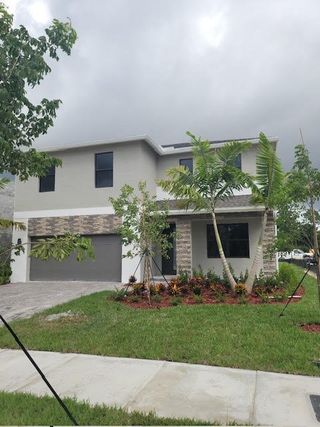 A modern two-story home with stone accents and lush landscaping in Rosemont by D.R. Horton (Miami, FL).