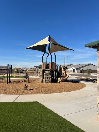 A welcoming playground with slides and shade in The Grove at El Cidro by William Ryan Homes (Goodyear, AZ).