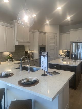 Model Home A contemporary kitchen with sleek white cabinets, quartz countertops, and modern lighting accents.