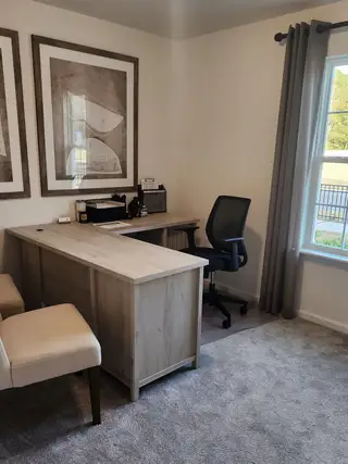A cozy home office with a light wood desk, modern chair, and large framed artwork enhancing the productivity space.