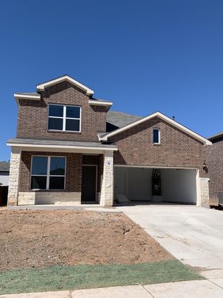 A modern brick home with a large garage in Lagos by Pulte Homes (Manor, TX).