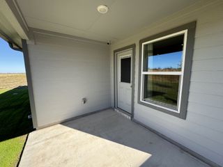A cozy covered patio with modern siding and a soft gray door.
