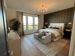A sophisticated bedroom with floor-to-ceiling windows, plush seating, and a statement chandelier.